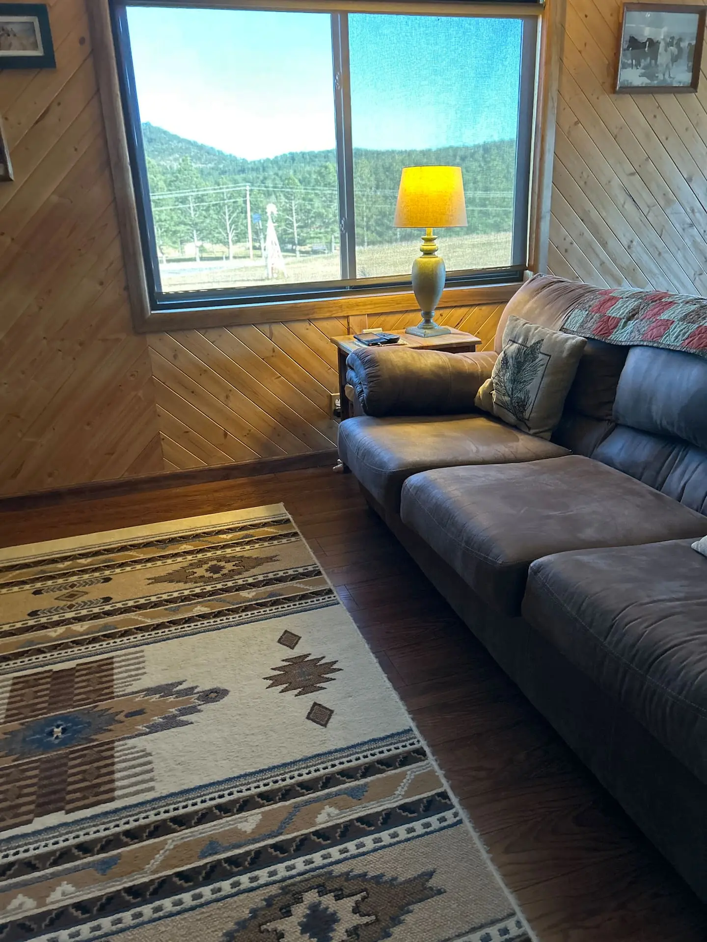 Living room with a deep leather couch, Southwestern rug and a large window looking out to the hills